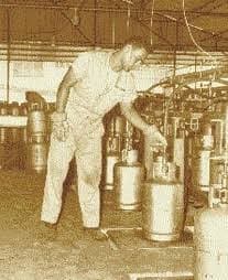 Fotografía de archivo en sepia: un trabajador llena cilindros de gas en una planta.