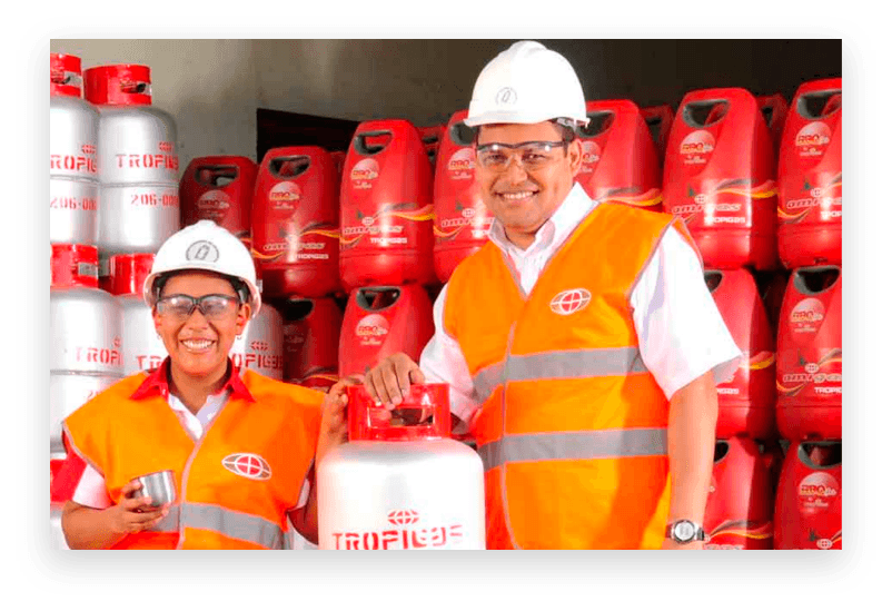 Dos trabajadores de Tropigas con casco y chaleco reflectivo frente a cilindros de gas apilados