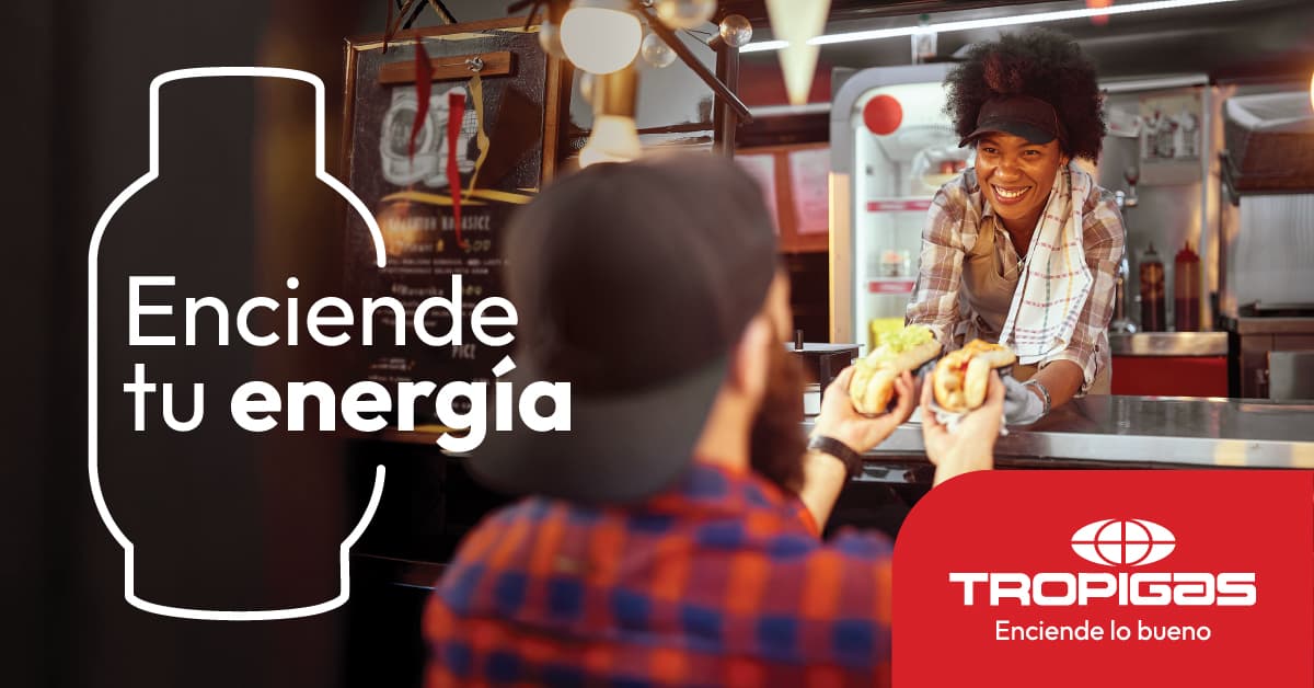 Enciende tu energía. Tropigas: una vendedora entrega comida a un cliente en su food truck.